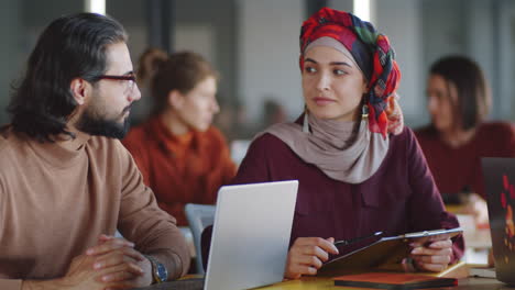 Mujer-En-Hiyab-Discutiendo-Negocios-Con-Un-Compañero-De-Trabajo-Masculino